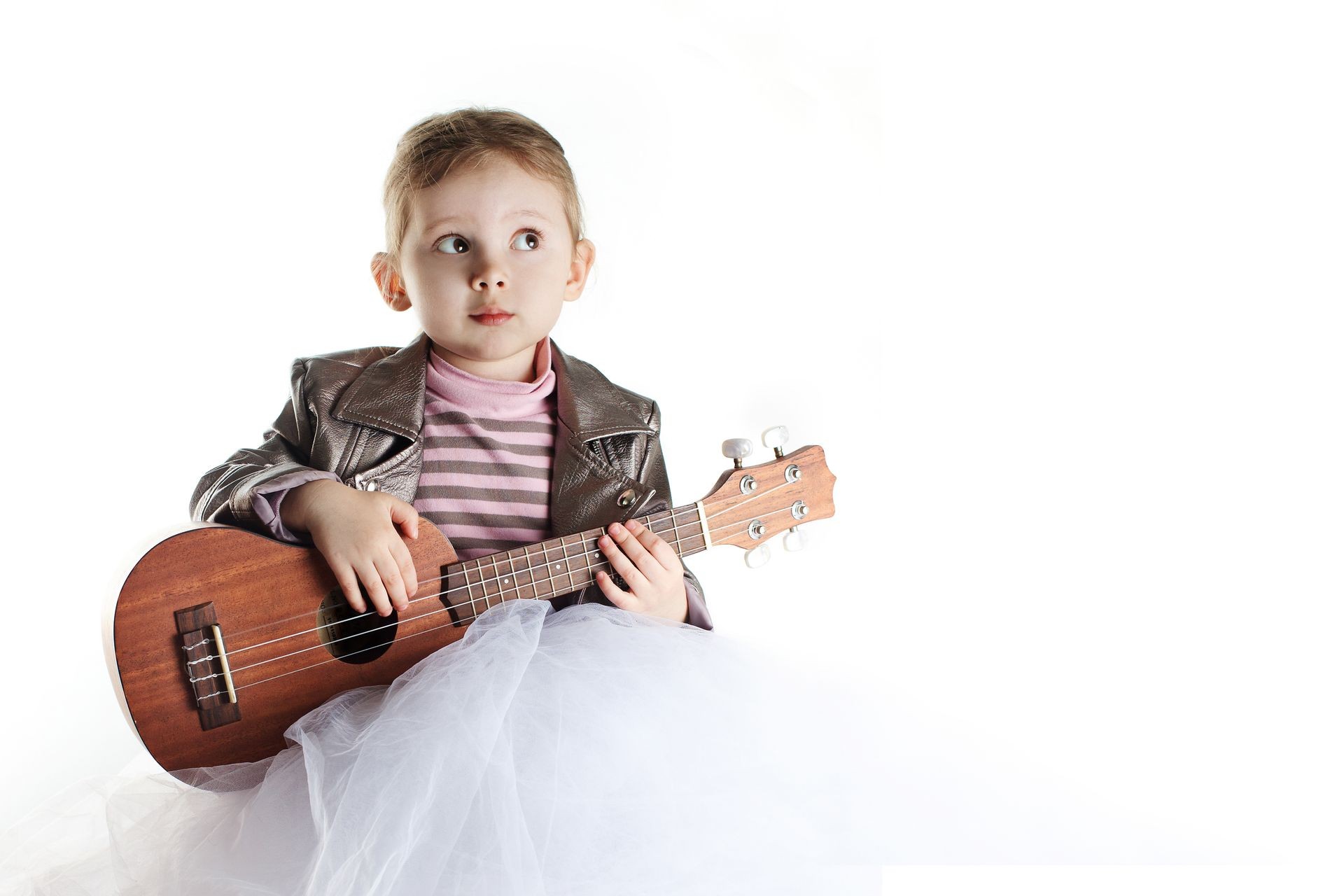 A portrait of caucasian toddler girl with ukulele on white background