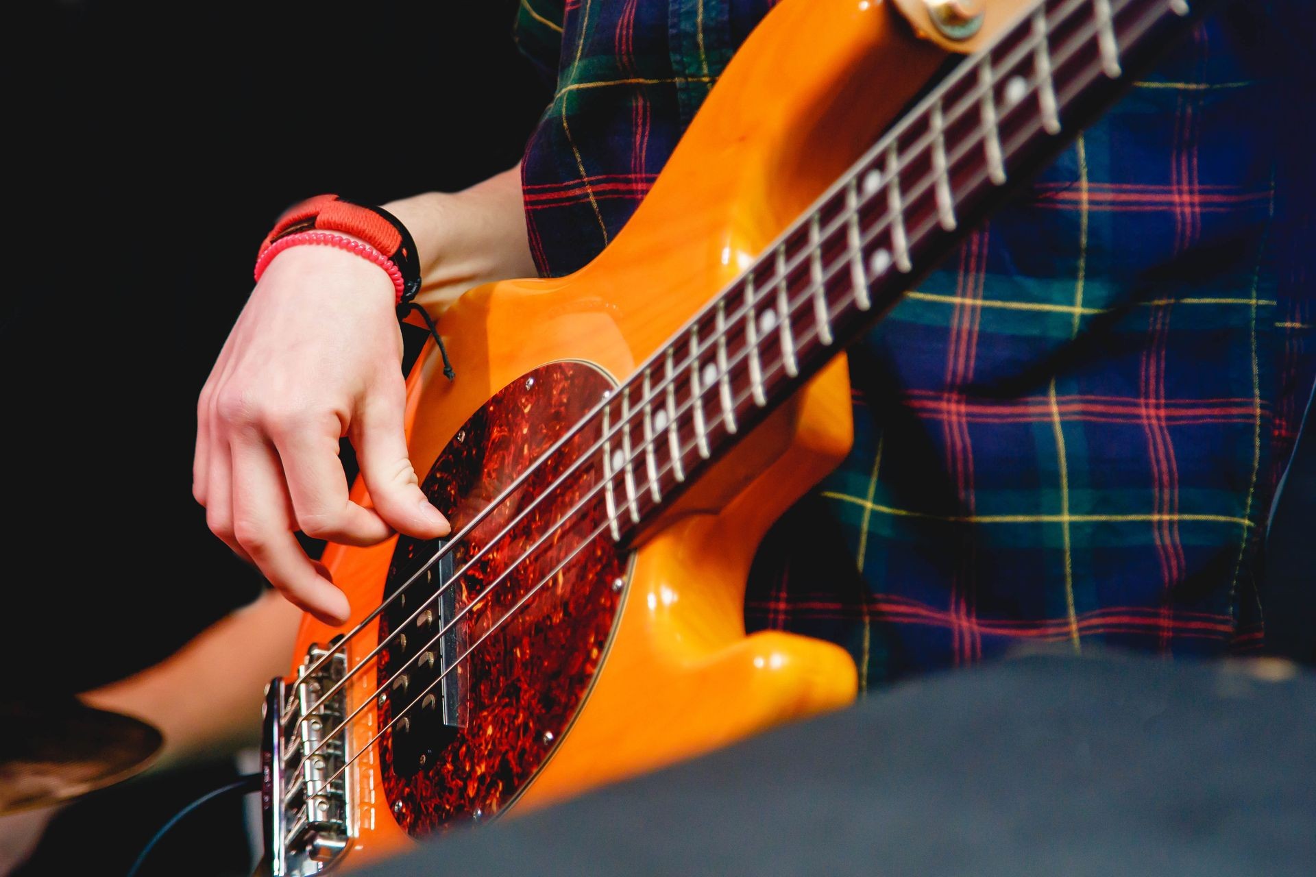 Closeup of hands of a man playing electrical bass guitar